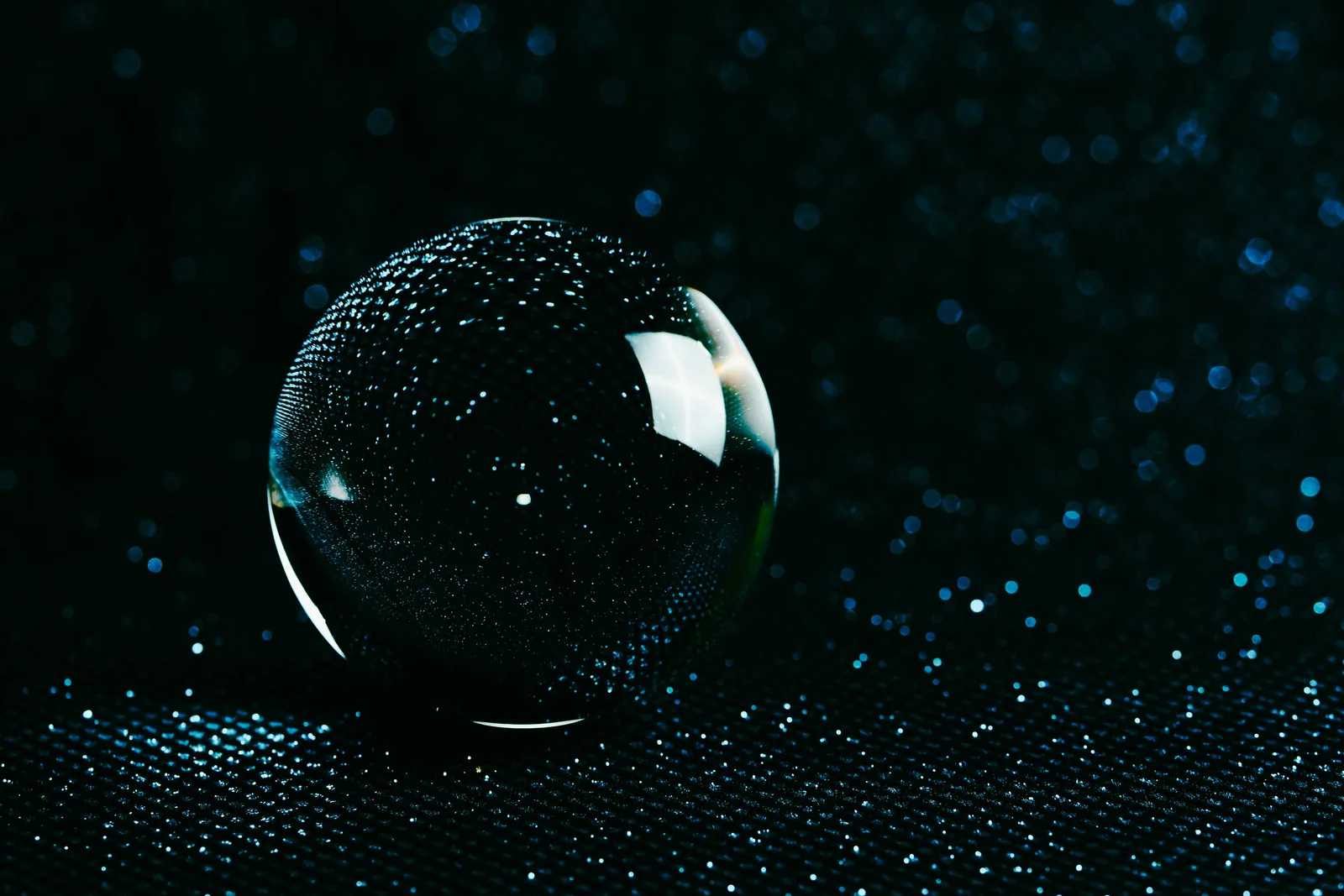 Glowing glass sphere covered in droplets on a dark textured surface